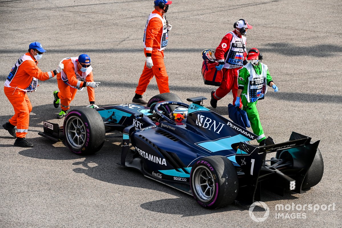 Los oficiales de pista con el monoplaza de Juri Vips, Dams después de hacer un trompo en la salida de la carrera