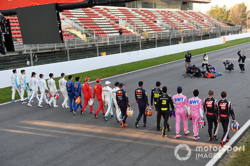 The drivers walk along the track toward a group of photographers