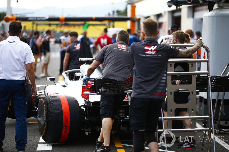 Haas team members guard a Haas F1 Team VF-18 in the pit lane