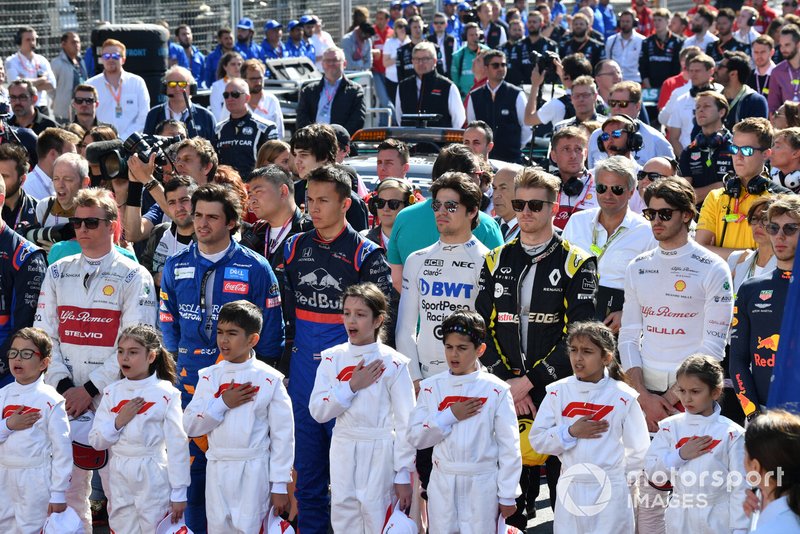 The drivers and Grid Kids stand for the national anthem prior to the start