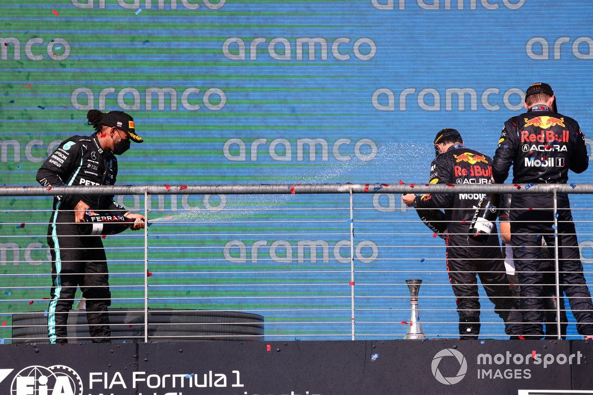 Lewis Hamilton, Mercedes, 2nd position, Sergio Perez, Red Bull Racing, 3rd position, and Max Verstappen, Red Bull Racing, 1st position, spray Champagne on the podium