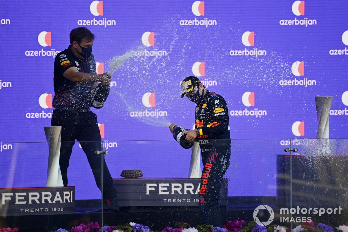 The Red Bull trophy delegate and Sergio Perez, Red Bull Racing, 1st position, celebrate with Champagne