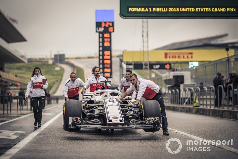 Mekanik mendorong mobil Alfa Romeo Sauber C37 di pit lane