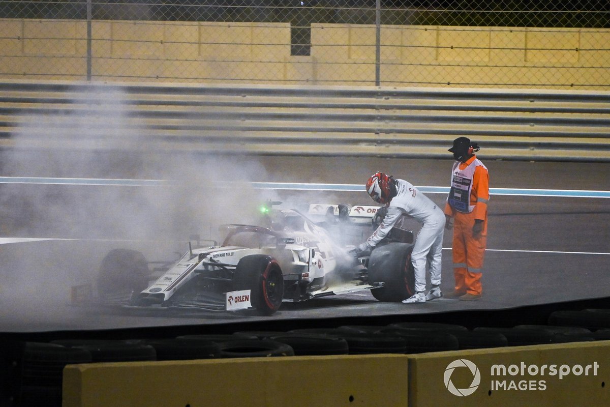 Kimi Raikkonen, Alfa Romeo Racing C39, assists a marshal in extinguishing a fire in his car