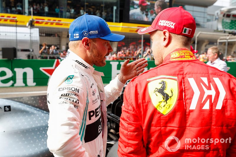 Valtteri Bottas, Mercedes AMG F1, talks to Sebastian Vettel, Ferrari, after securing pole position