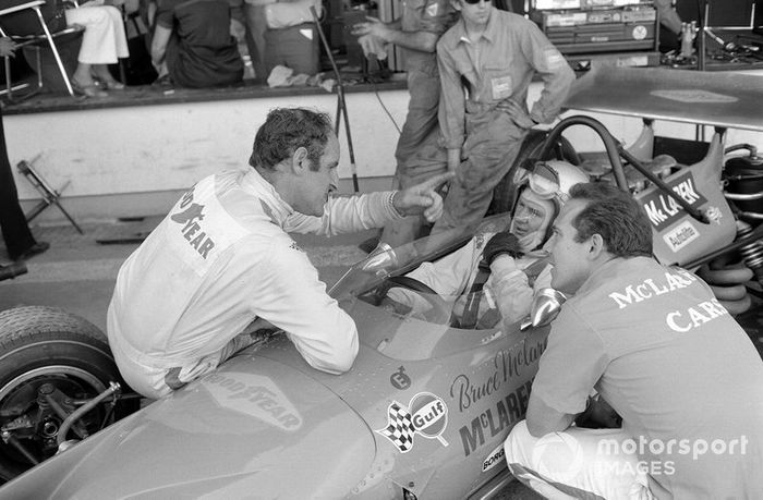 Denny Hulme habla con Bruce McLaren mientras está sentado en su Ford McLaren M14A en los pits