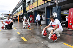 Les mécaniciens Sauber assèchent l'emplacement dans les stands