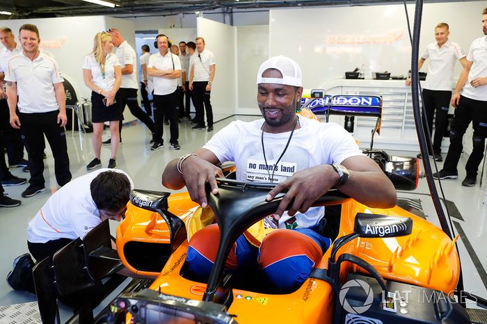 El jugador de baloncesto Serge Ibaka, de los Toronto Raptors en NBA e internacional con España, se intenta sentar en el McLaren de Fernando Alonso