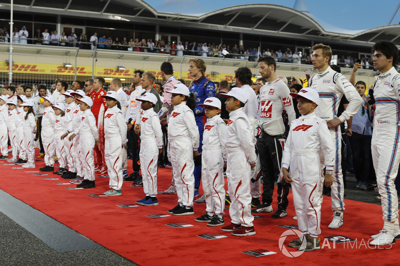 Drivers and mascots stand for the national anthem on the grid