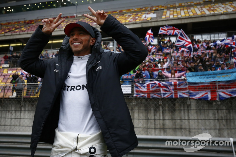 Lewis Hamilton, Mercedes AMG, celebrates victory in front of a grandstand filled with fans waving Br