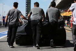 McLaren engineers move the car of Fernando Alonso, McLaren MCL32, in the pit lane, under covers