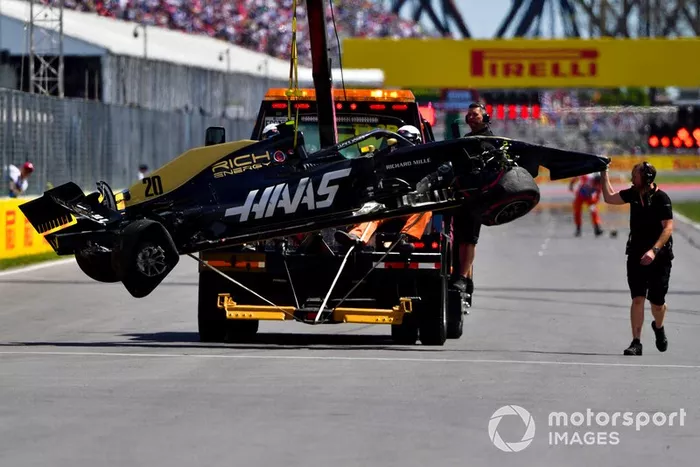 Oficiales retiran el coche dañado de Kevin Magnussen, Haas F1 Team VF-19, del circuito