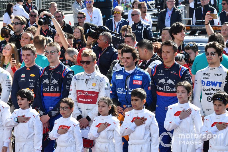 The drivers and Grid Kids stand for the national anthem prior to the start