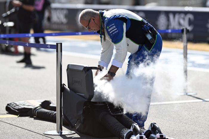 Racing Bulls team member on the grid with cooling equipment