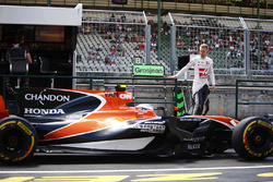 Kevin Magnussen, Haas F1 Team, climbs down from the pit wall as Stoffel Vandoorne, McLaren MCL32, passes