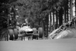 Dan Gurney repteti az Eagle-Climax T1G-et, miközben elhalad egy versenyautó roncsa mellett Bruennchenben