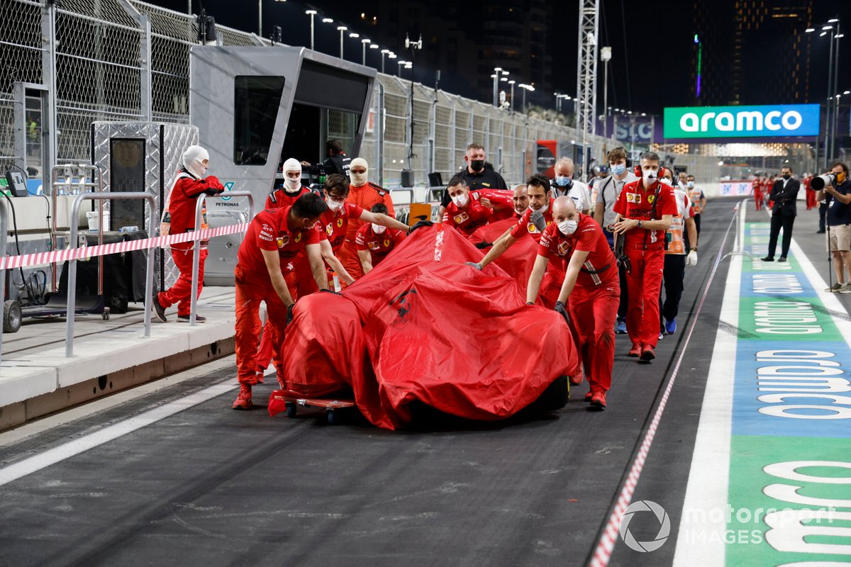 Mecánicos con el coche dañado de Charles Leclerc, Ferrari SF21, bajo una lona en el pit lane