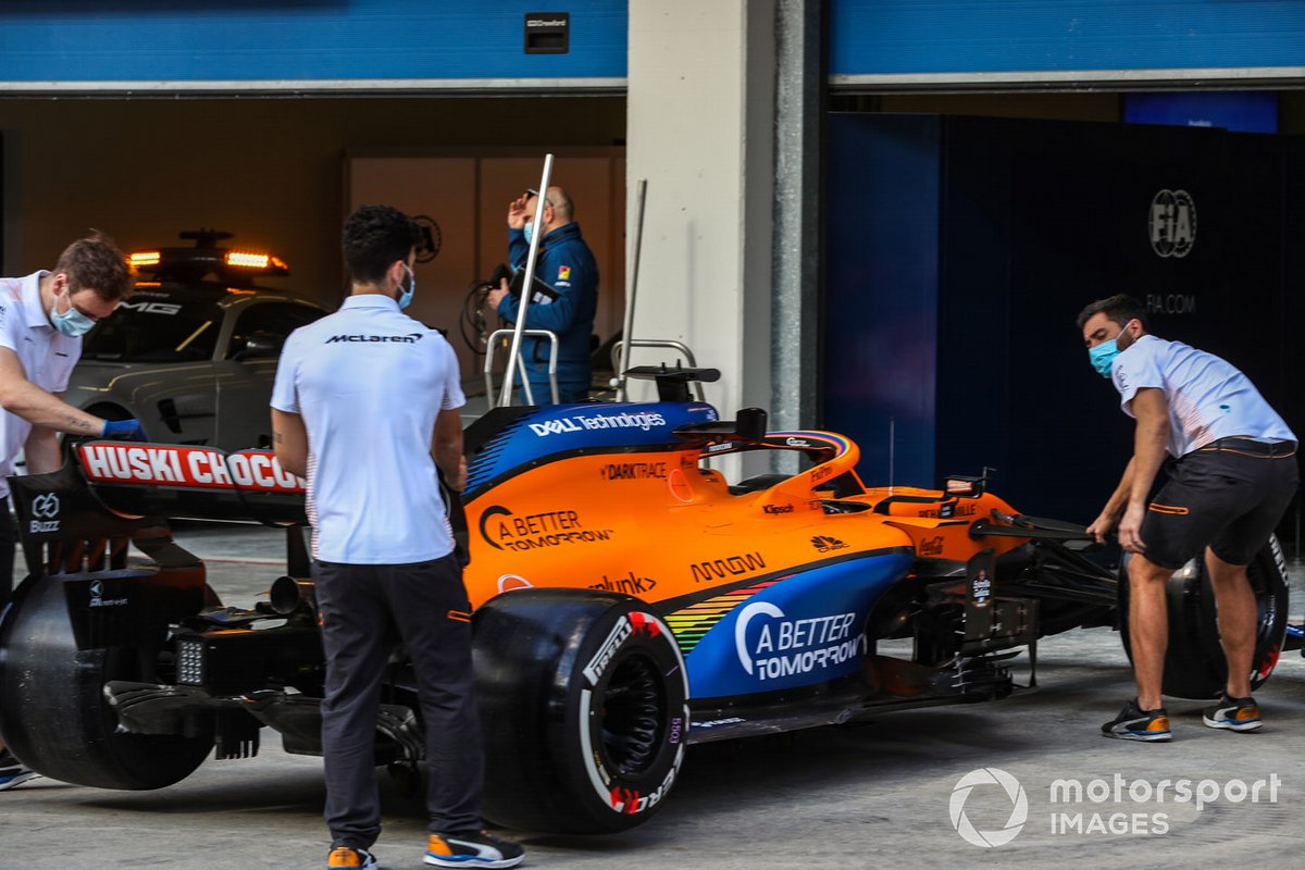 McLaren personnel with one of their cars outside the garage