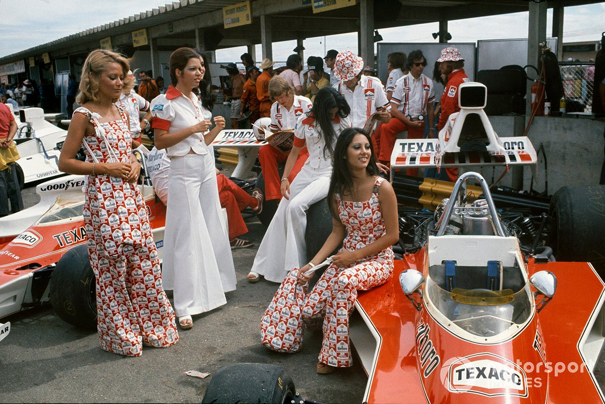 Marlboro girls and McLaren mechanics with McLaren M23 Fords in the pits