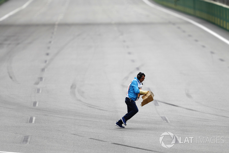 A marshal collects debris from the track