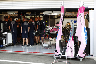 Des mécaniciens rassemblés dans le garage de Force India près de la monoplace de Sergio Perez Force India VJM11