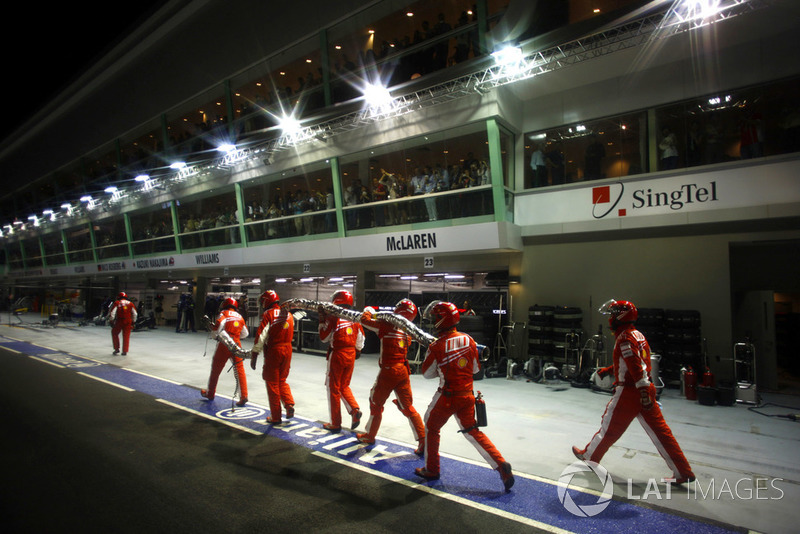 Les mécaniciens Ferrari ramènent le tuyau de ravitaillement en essence au garage