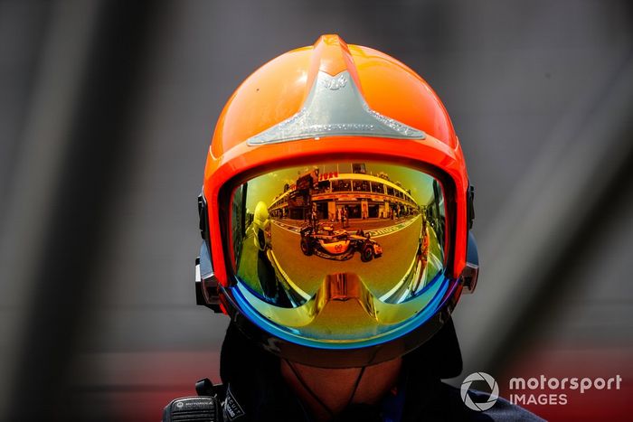 Lando Norris, McLaren MCL36, reflejado en el visor de un bombero