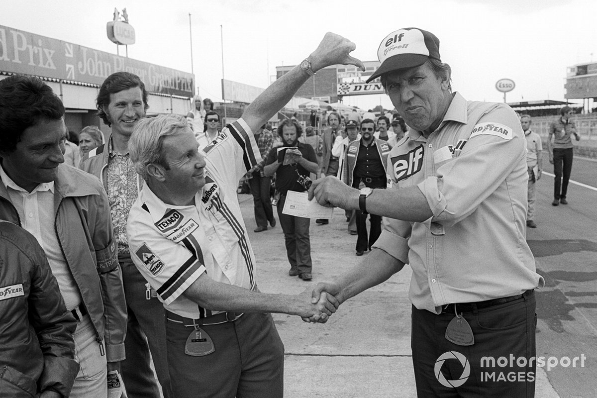Teddy Mayer, McLaren Team Owner hands over a cheque to Ken Tyrrell, Tyrrell Team Owner after losing a pit stop tyre change competition