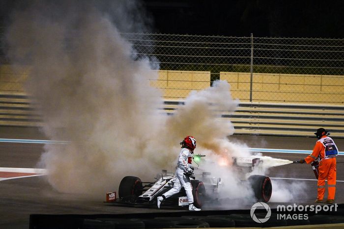 Kimi Raikkonen, Alfa Romeo Racing C39, ayuda a un oficial de pista a apagar el incendio de su monoplaza