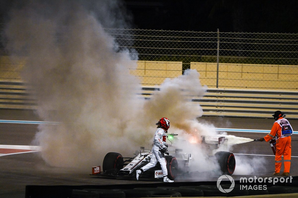 Kimi Raikkonen, Alfa Romeo Racing C39, assists a marshal in extinguishing a fire in his car