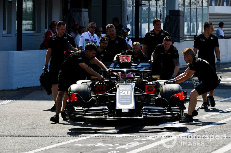 Mechanics move the car of Kevin Magnussen, Haas F1 Team VF-19