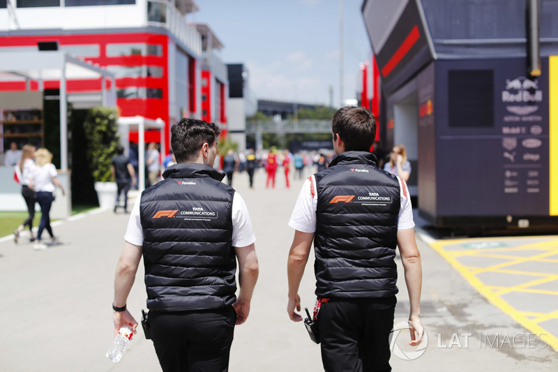 Dos hombres vestidos con ropa de marca TATA caminan por el paddock