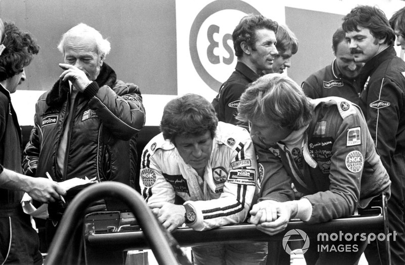 Mario Andretti and Ronnie Peterson talk in the pit lane with team boss Colin Chapman, Lotus