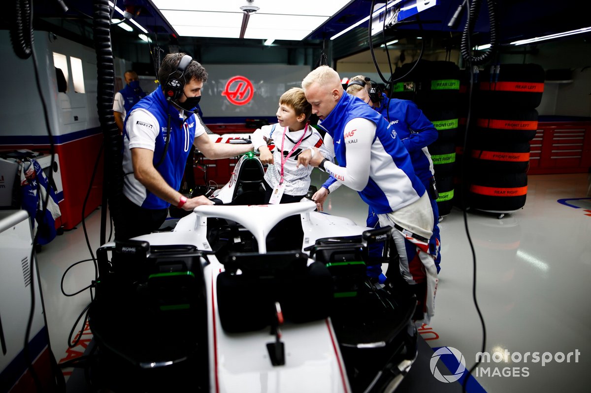 Nikita Mazepin, Haas F1, shows a child around the cockpit of his car