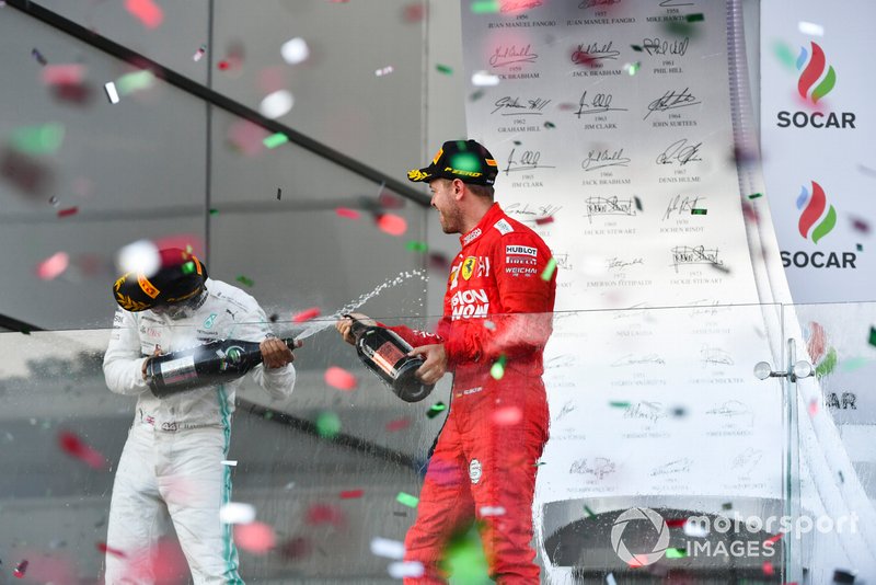 Lewis Hamilton, Mercedes AMG F1, 2nd position, and Sebastian Vettel, Ferrari, 3rd position, spray Champagne at each other on the podium