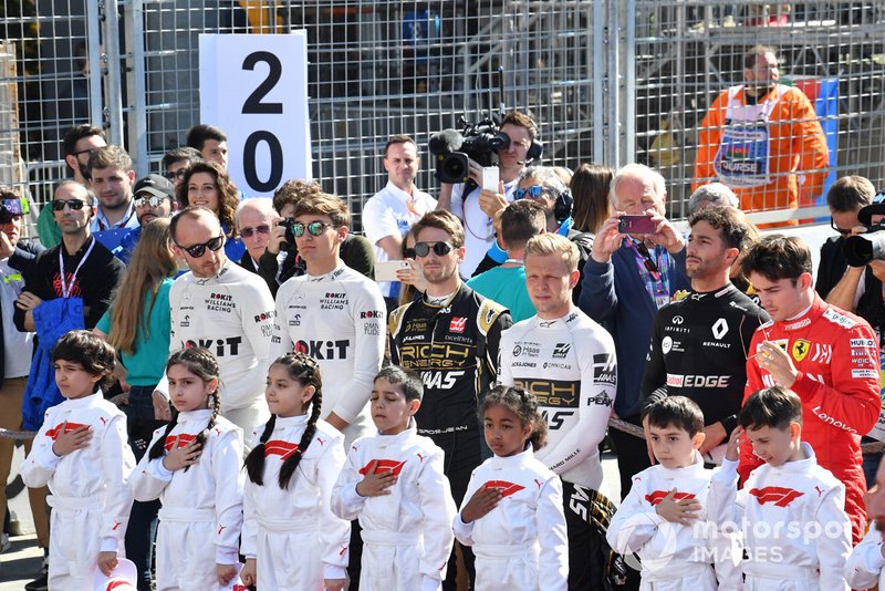 The drivers and Grid Kids stand for the national anthem prior to the start