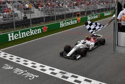 Charles Leclerc, Sauber C37 takes the chequered flag waved by Winnnie Harlow (CDN)