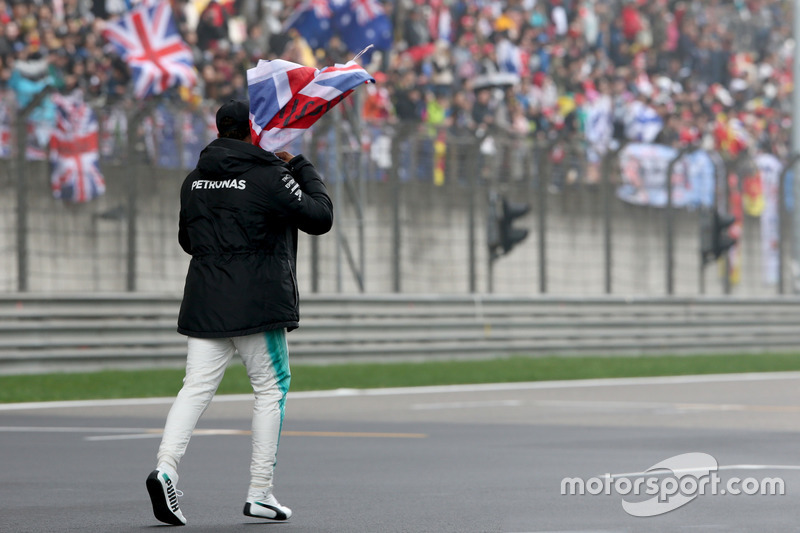 Lewis Hamilton, Mercedes AMG, attraversa la pista per intrattenere i tifosi e raccoglie una bandiera