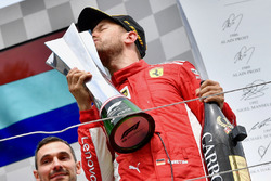 Race winner kisses the trophy and celebrates on the podium