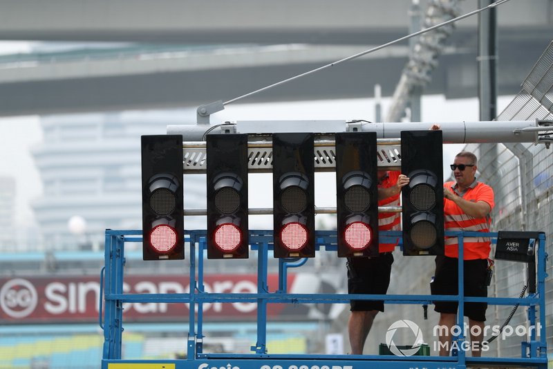Workers adjust the start light gantry, which has lights set to red