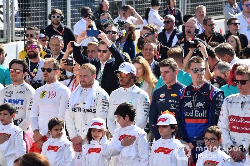 The drivers and Grid Kids stand for the national anthem prior to the start