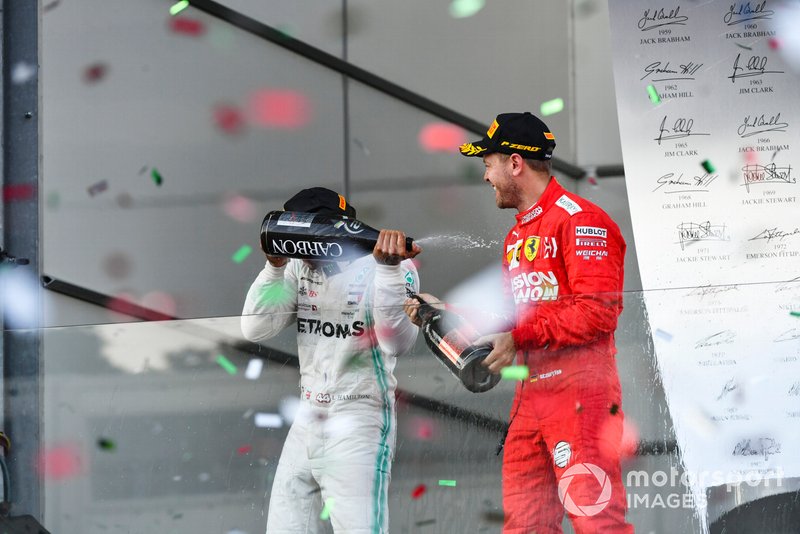 Lewis Hamilton, Mercedes AMG F1, 2nd position, and Sebastian Vettel, Ferrari, 3rd position, spray Champagne at each other on the podium