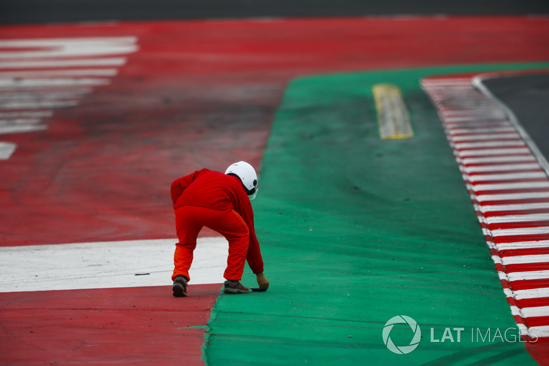 Un oficial recoge un pedazo de escombros de la pista