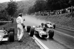 Jo Siffert, Lotus has just stopped for borrowing a dry visor from retired Graham Hill. John Surtees, Honda is passing the pair