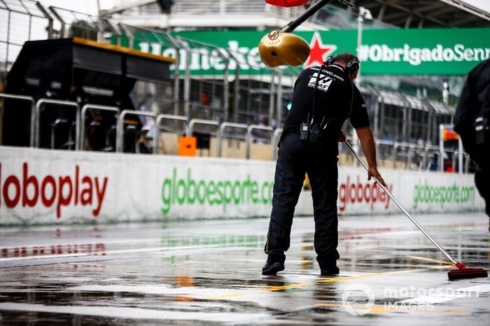 Un mecánico de Haas barre el agua del exterior del garaje