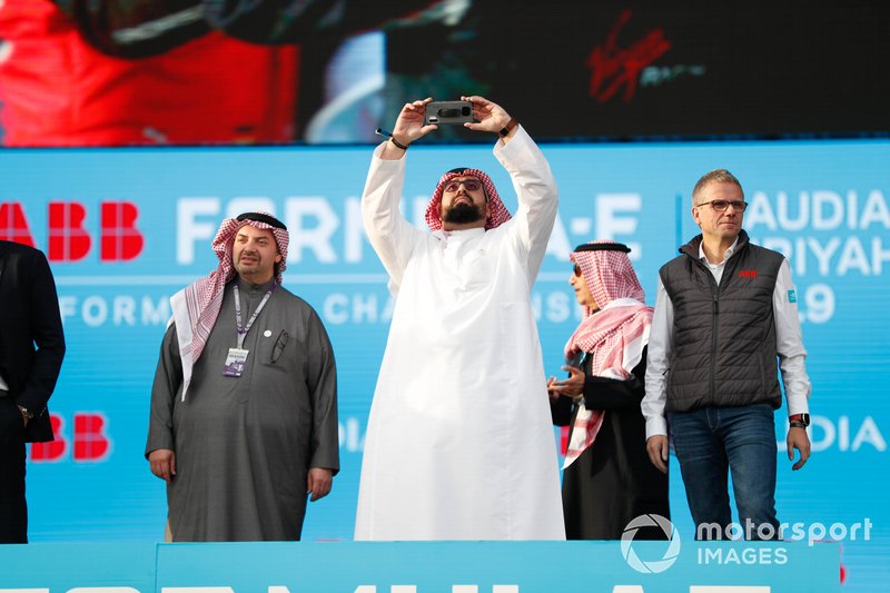 A Saudi VIP takes a photo from the podium