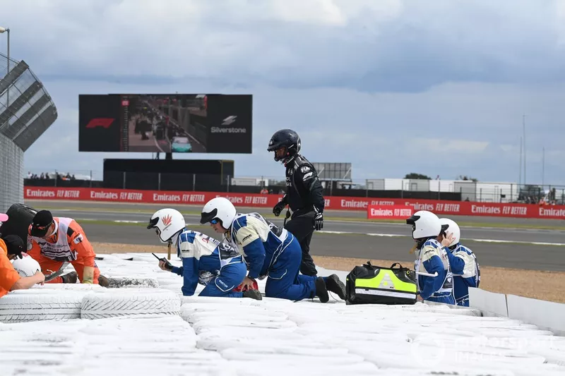 Los oficiales de pista y médicos asisten a Zhou Guanyu, Alfa Romeo C42