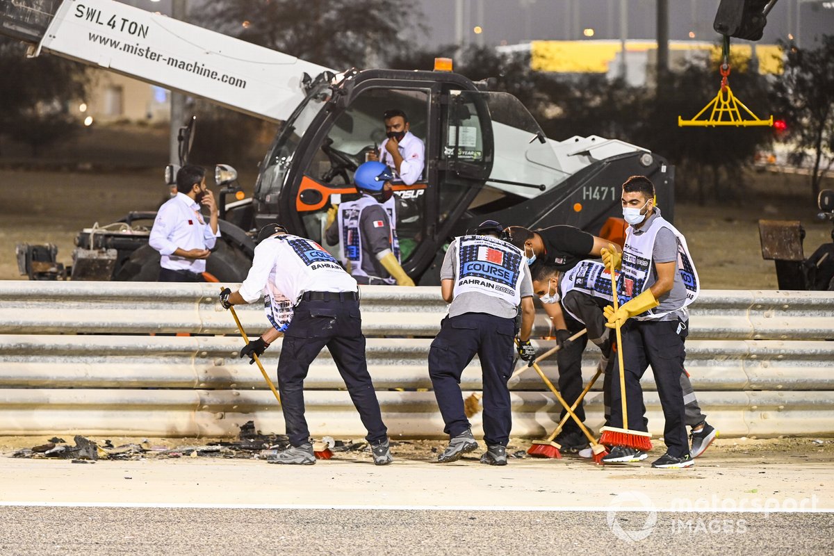 Marshals sweep up debris after a huge first lap crash for Romain Grosjean, Haas F1