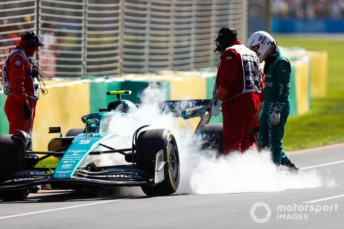 Oficiales de pista asisten a Sebastian Vettel, Aston Martin AMR22, tras abandonar en la FP1