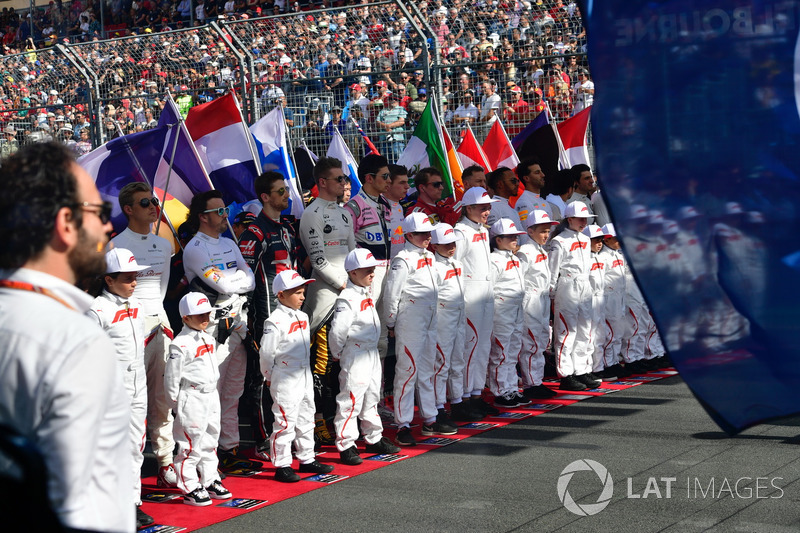 Drivers and grid kids observe the National Anthem on the grid